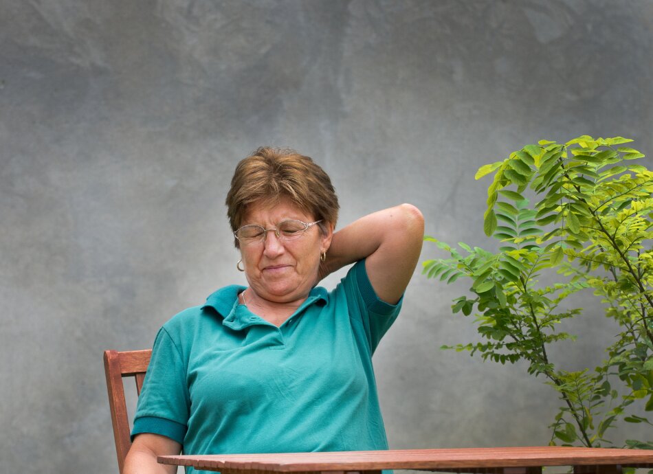 Woman reaches behind to rub sore neck