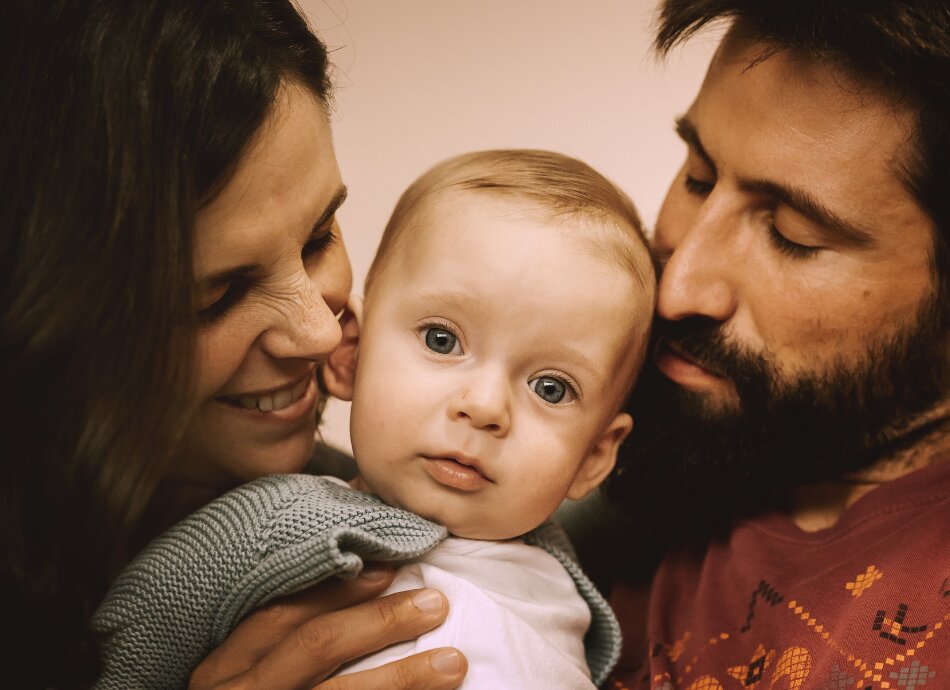 Parents hug and smile with baby