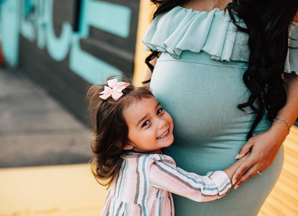 Cute little girl hugs pregnant mother's tummy